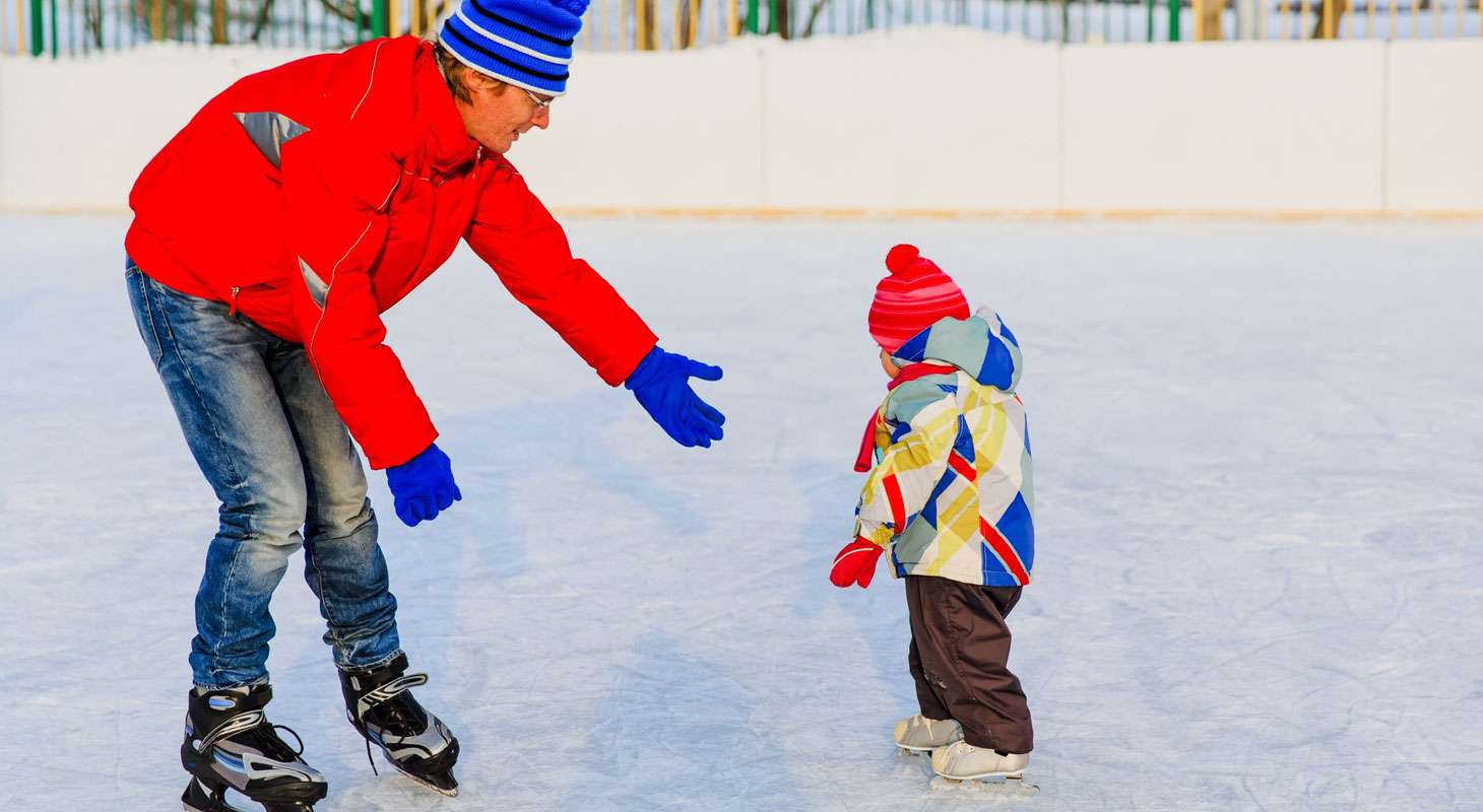 Father teaching little daughter to skate in Vermont