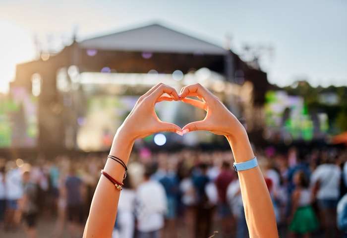 Concertgoer forms heart shape with hands in front of stage