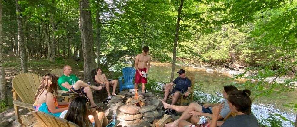 A family gathered around the fire pit at Warren Lodge, a family reunion venue in the Mad River Valley in Vermont