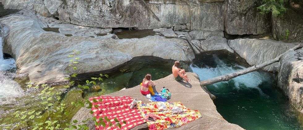 A couple sitting on the rocks next to Warren Falls in Vermont.