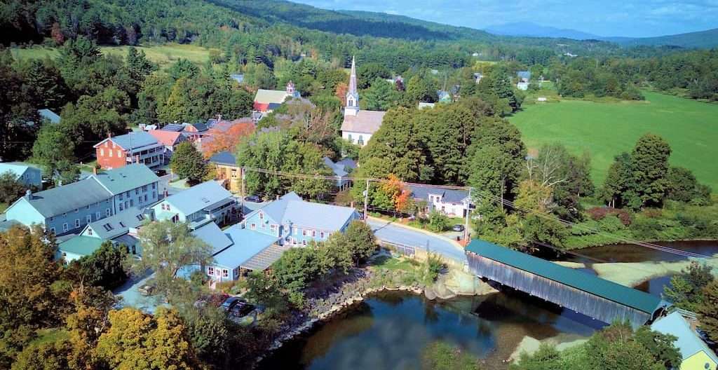 Overhead view of a small town in Vermont, featuring a river and the iconic Waitsfield covered bridge.