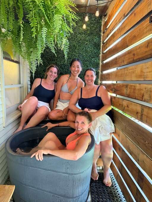 A group of women sitting around a cold plunge tub at Drip Culture Saunas in Waitsfield, Vermont, during a girls' weekend getaway