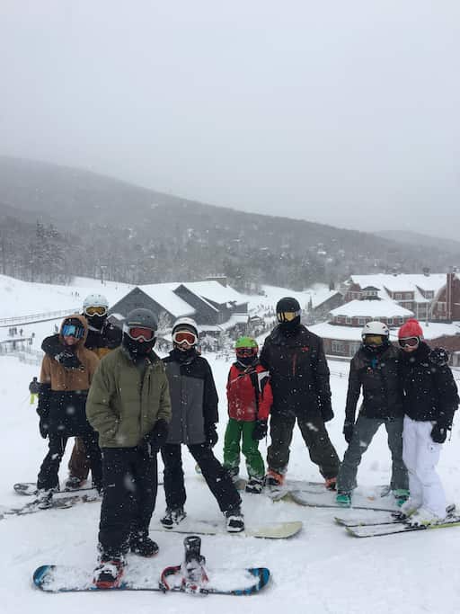 A group of friends dressed in ski gear on their snowboards during a Vermont winter getaway.