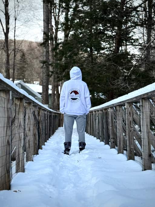A solo traveler walking down a snow-covered bridge during a Vermont winter getaway.