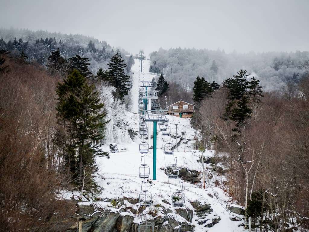Skiers holding their skis over their shoulders as they walk out of the entrance area for Mad River Glen Ski Cooperative