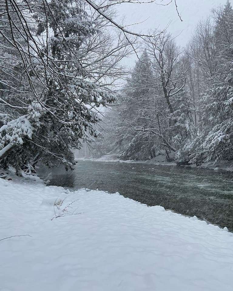 Snow falling around the Mad River in the backyard of our Vermont lodge
