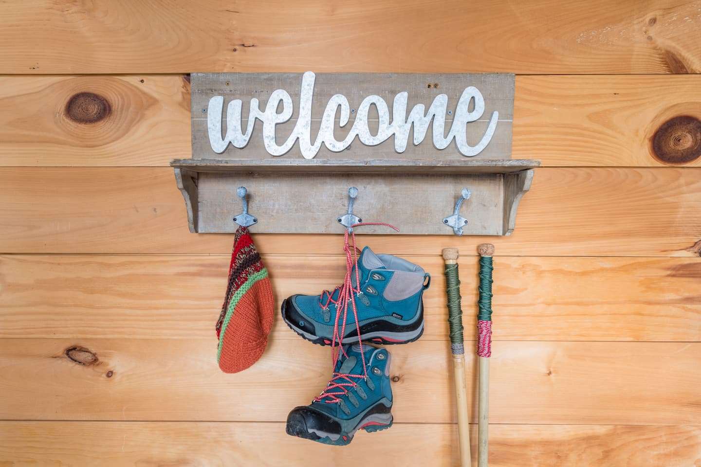 A welcome sign at Warren Lodge in Vermont with hooks below holding hiking gear