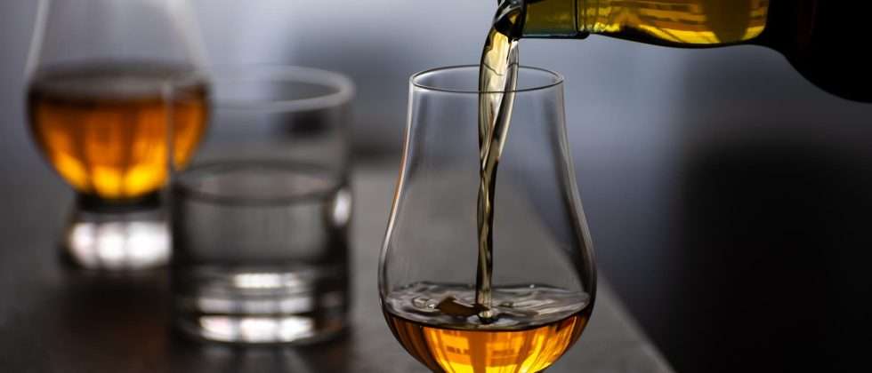 Someone pouring a glass of whiskey at a Vermont distillery