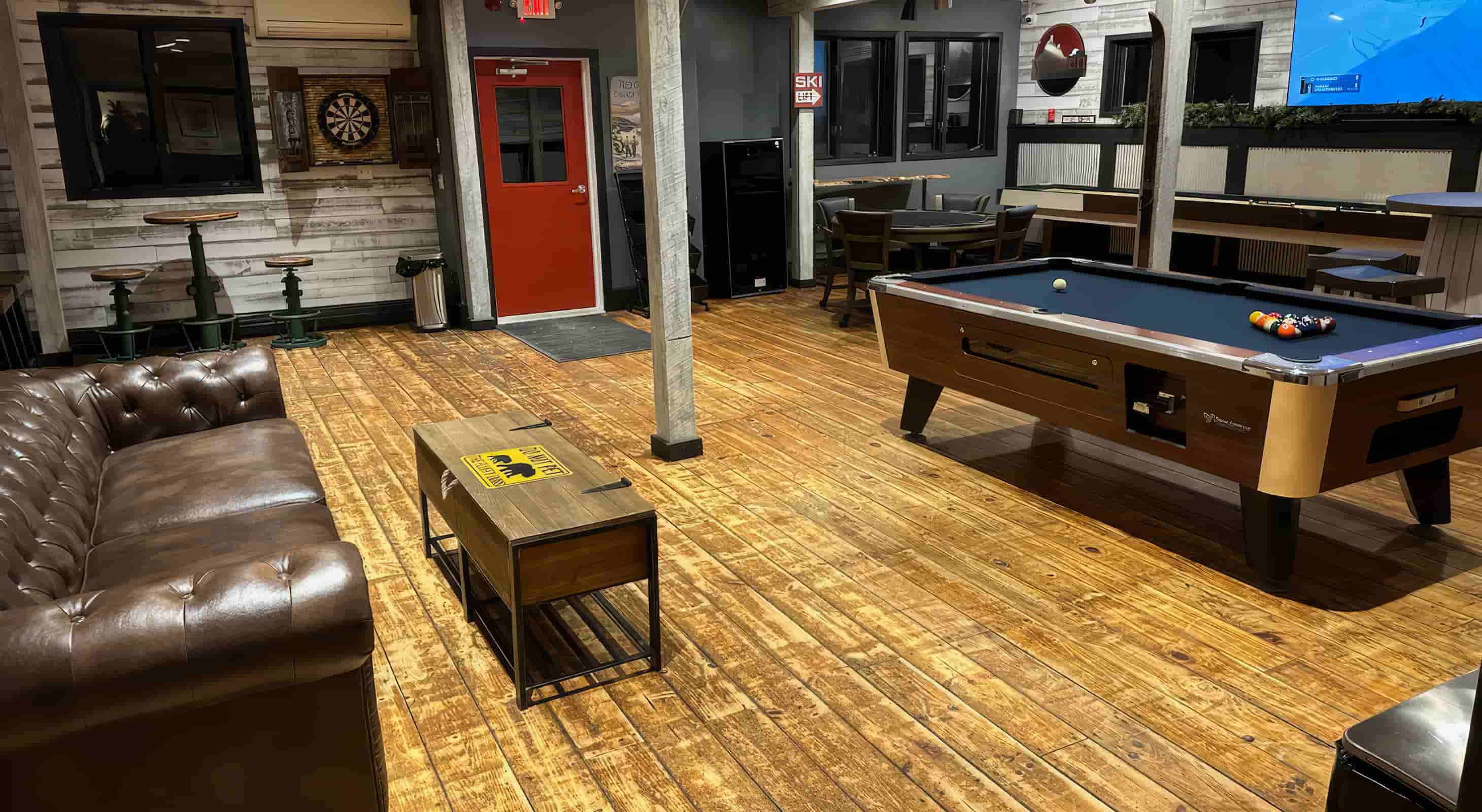 Gameroom with pool table, darts, large tv, leather couch, and more in a VT Whole Lodge Rental
